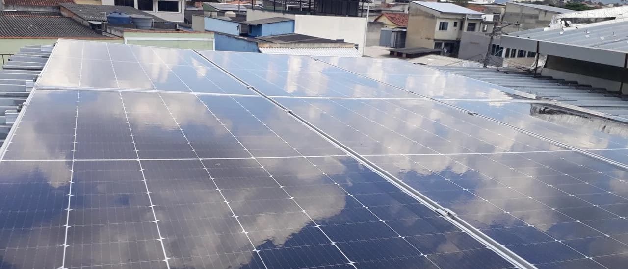 Módulos fotovoltaicos refletindo o céu em telhado metálico