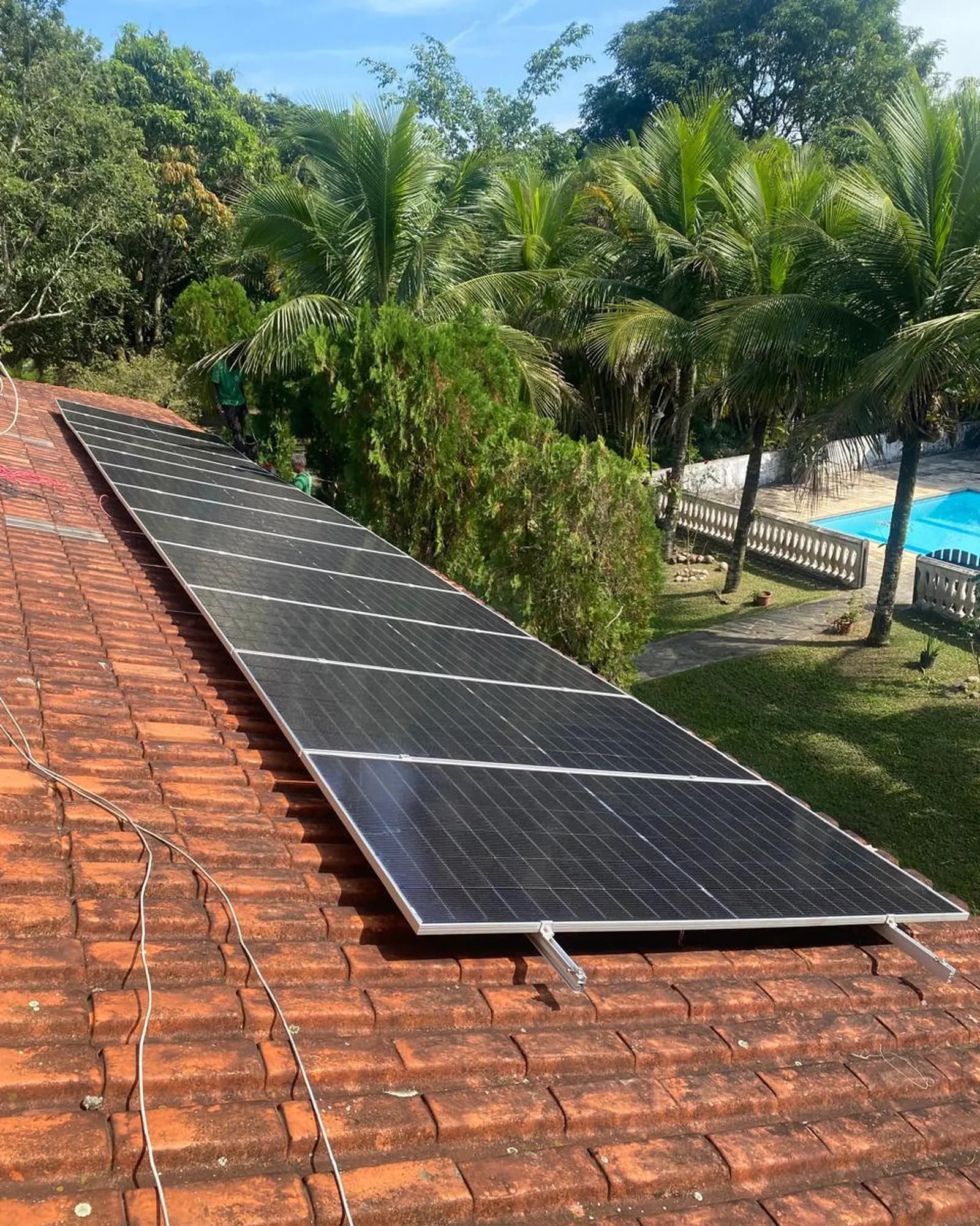 Sistema fotovoltaico instalado em telhado de sítio com piscina ao fundo