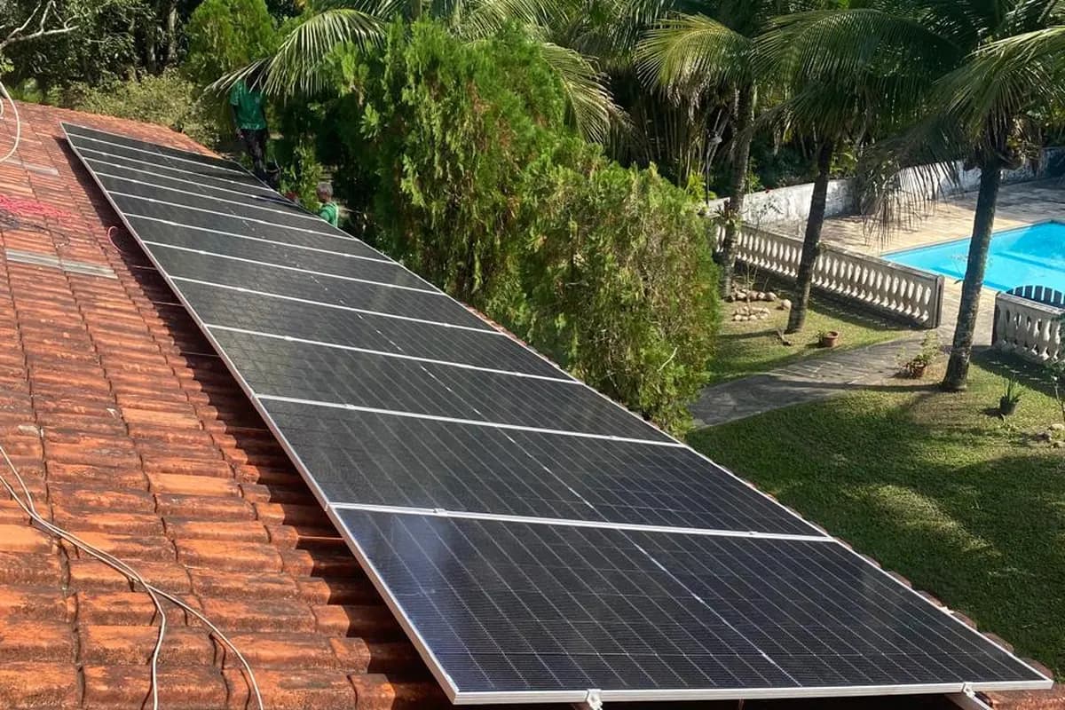 Sistema fotovoltaico instalado em sítio, com área de lazer e piscina ao fundo